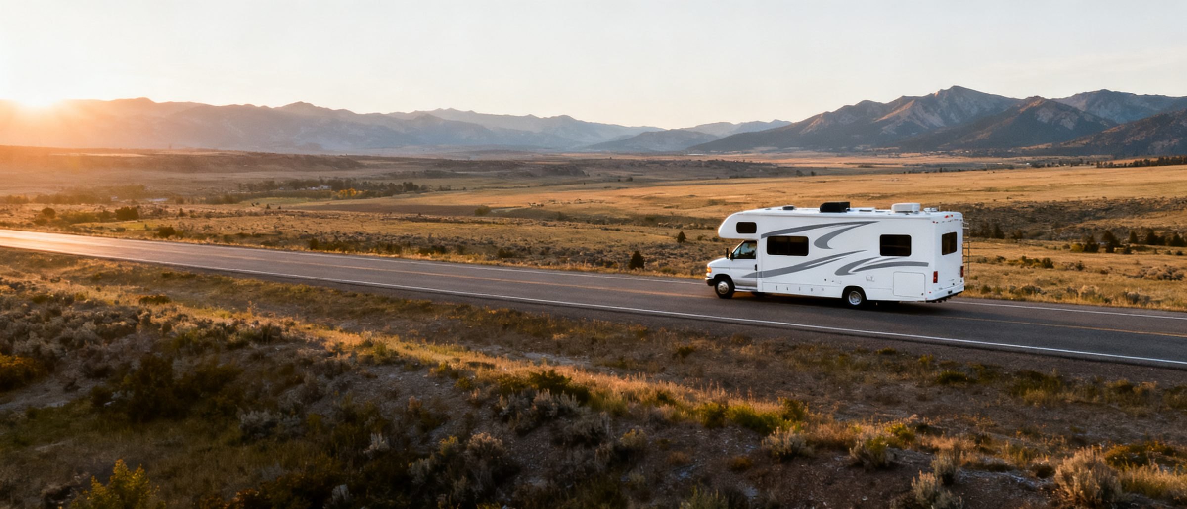 A motorhome on an open two-lane highway through a wide Western valley